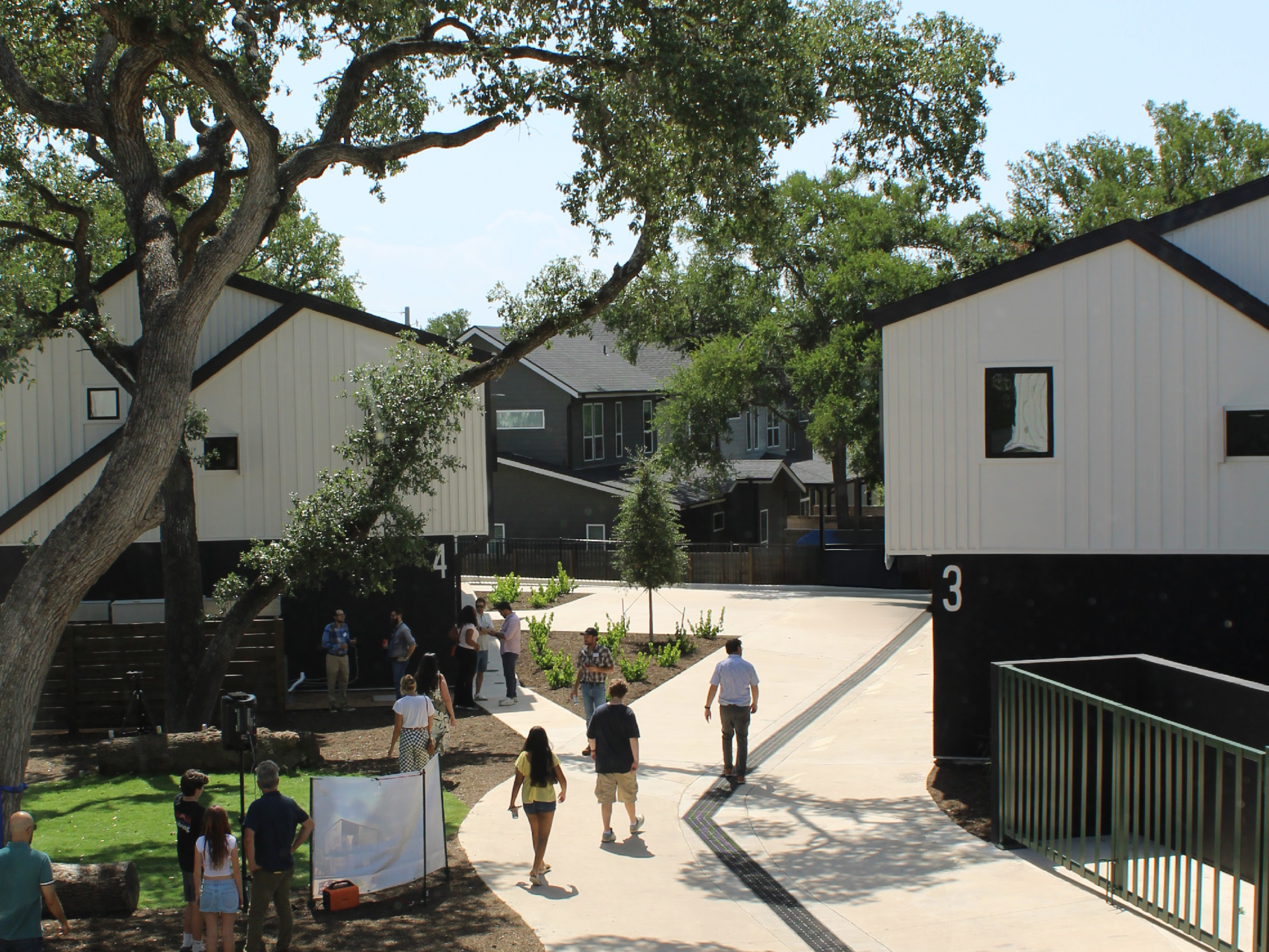 Image shows view of Industry SOMA townhomes and grounds from an upstairs window of a three bedroom unit. Below people can be seen walking the ground and talking under the shade of trees.