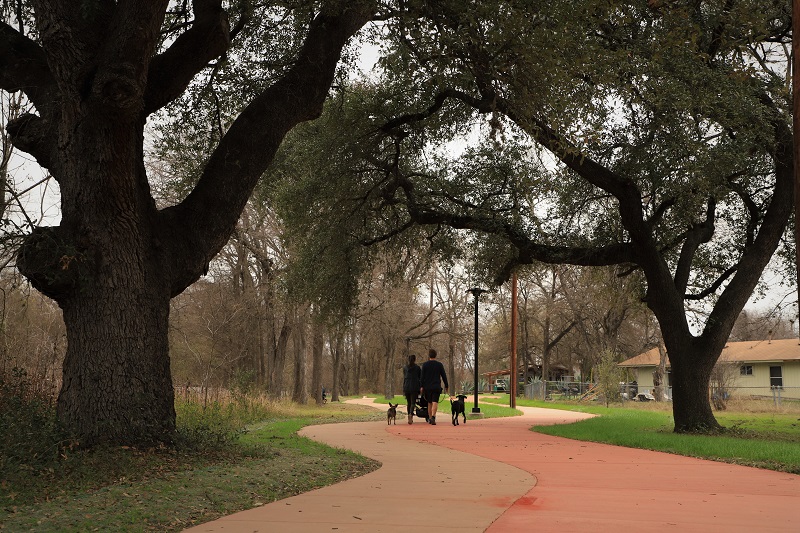 A family enjoys a stroll along the new dual-track trail along Boggy Creek. A family walks with their dogs along the new dual-track Boggy Creek Trail.
