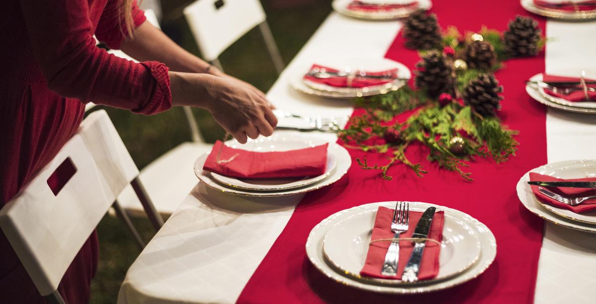 Woman sets table for a holiday meal. 