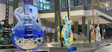 Huge painted guitars sit atop a baggage carousel at the airport. 