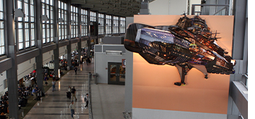 Dark, blimp-like ship floats above the concourse in the terminal.
