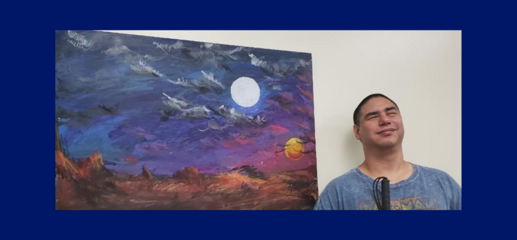 Joe smiles in front of one of his landscape paintings