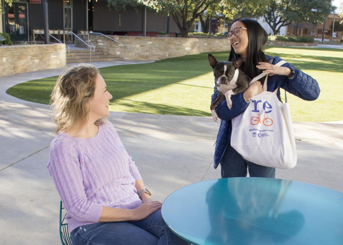 Woman carries her Boston Terrier in a reusable bag to meet a friend