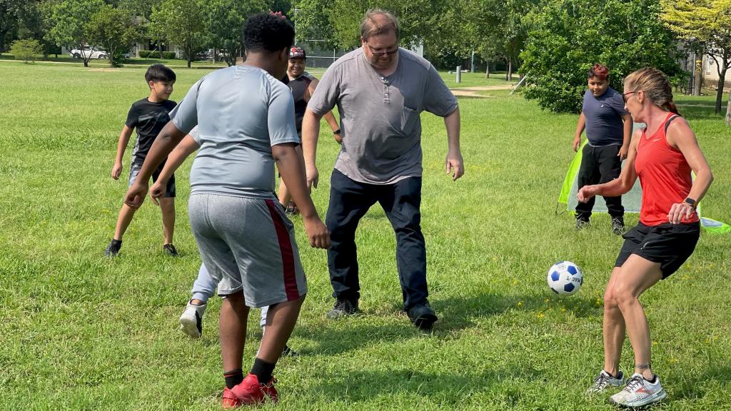 children and adults play soccer