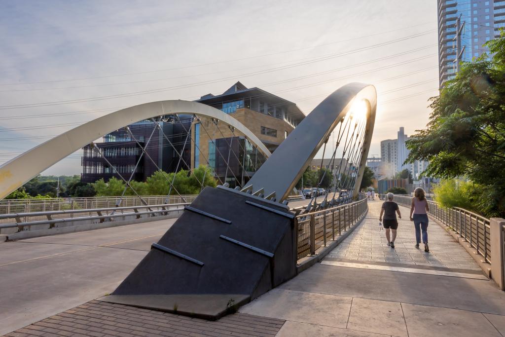 residents walking next to Butterfly Bridge on 2nd Street with the Austin Public Central Library showing behind the bridge