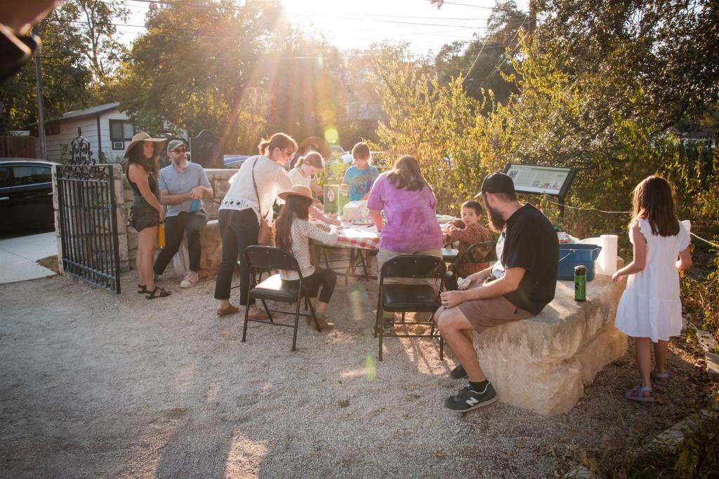 people outside doing crafts at a table in the sunshine
