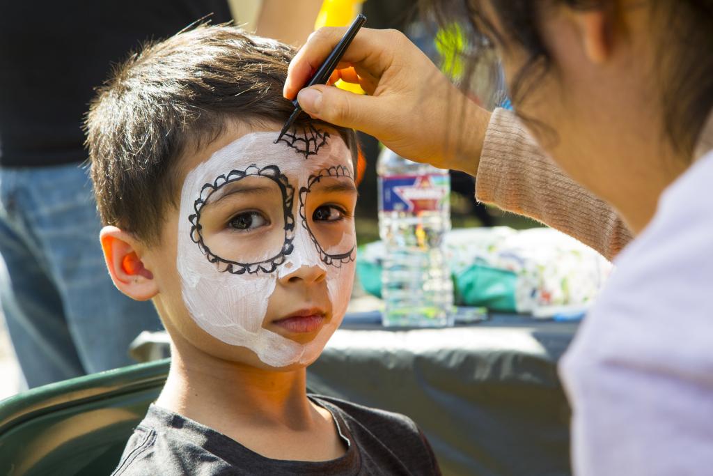 young kid getting facepaint for day of the dead
