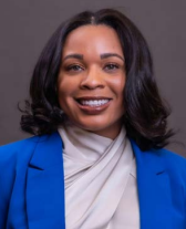 Dr. Wilson, a Black woman, smiles wide at the camera and is wearing a blue blazer.