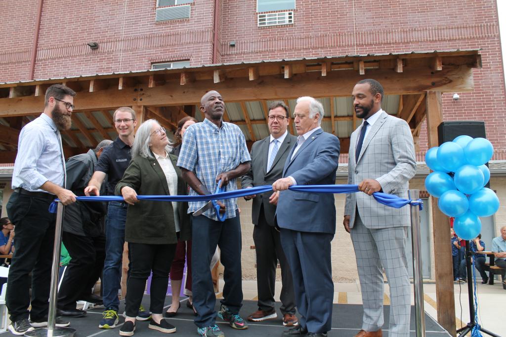 Image shows ribbon cutting with city officials, partners and residents. 