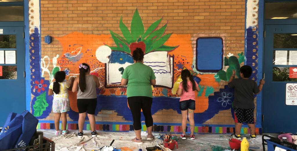 children and teacher painting mural