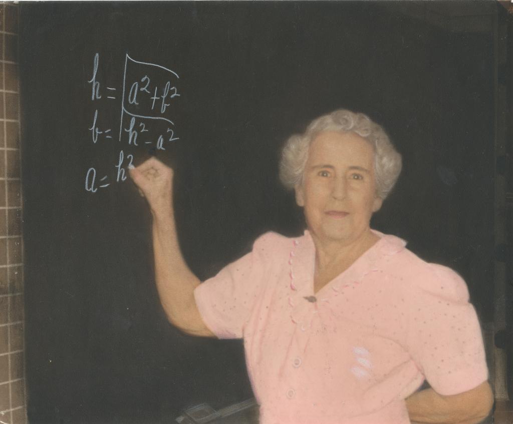 Woman in pink shirt writing on chalkboard