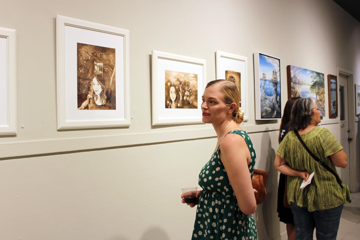 Woman looking at artwork and smiling in exhibit by Adrienne Hodge & Katie Ryan