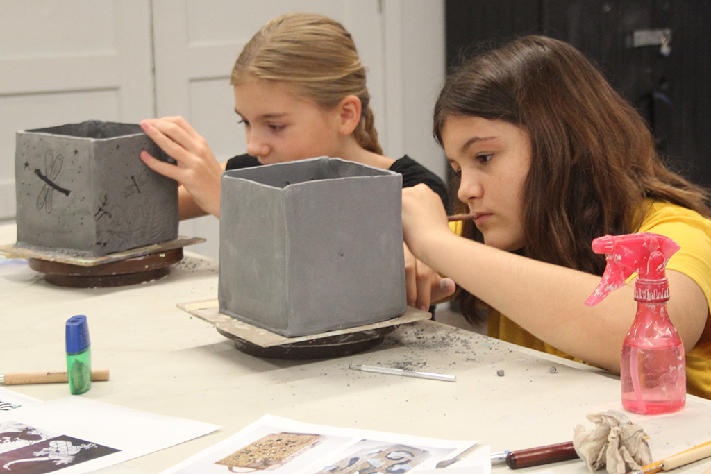 two students diligently work on three dimensional cube shaped ceramic vessels