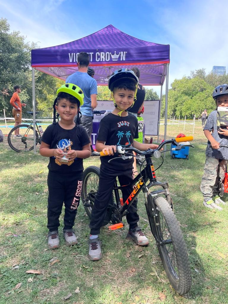 Children in bike helmets pose with a bike.