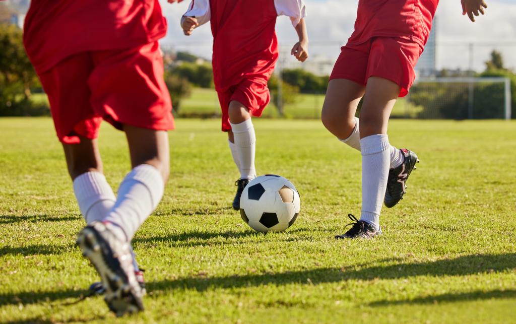 a soccer ball and three soccer players fro the waiste down