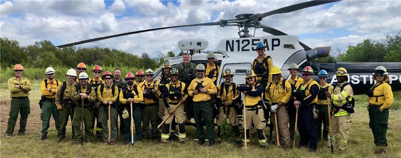 Firefighters standing in front of a helicopter.