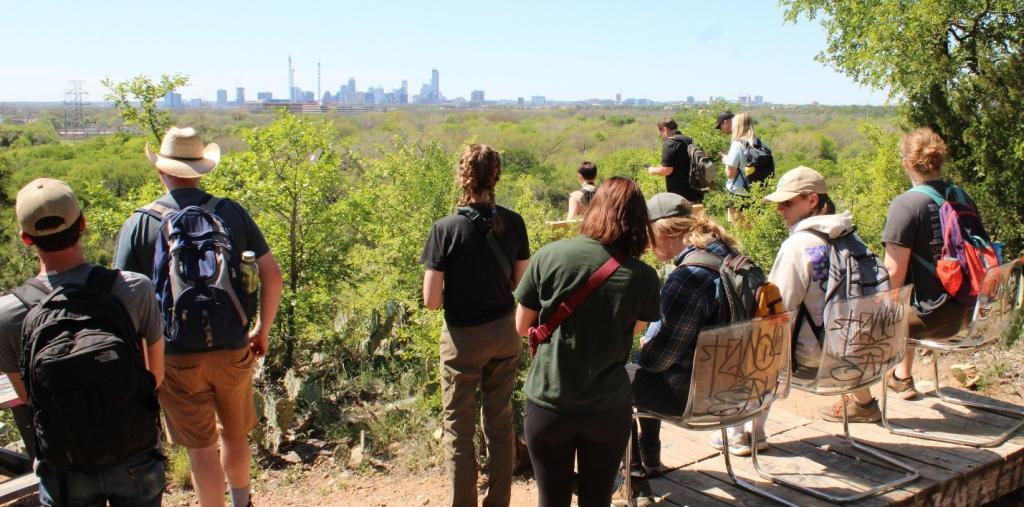 Students overlook Red Bluff Nature Preserve and the Austin skyline beyond. 