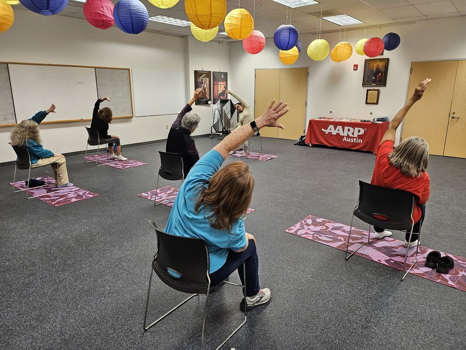 Group of people doing chair yoga indoors