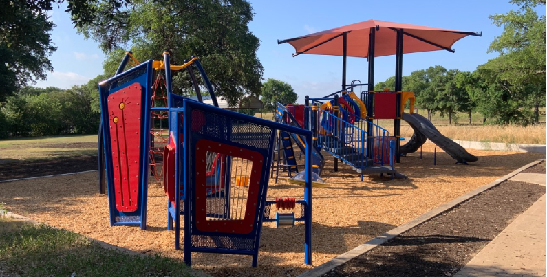 Photo of completed playground with shade structure, slides, and climbing elements.