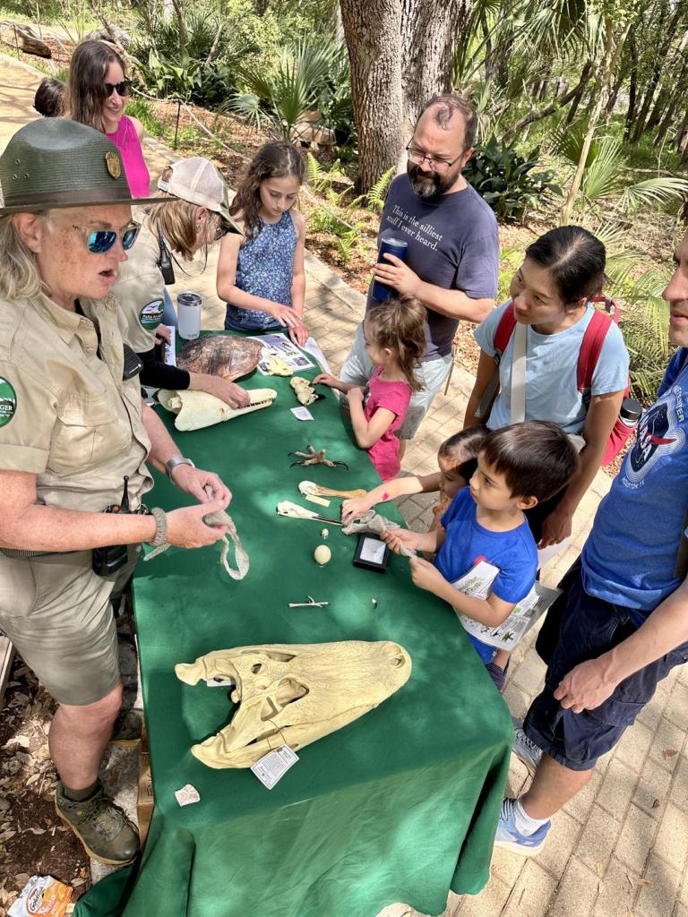 Rangers talking to people around a table with skins and skulls.