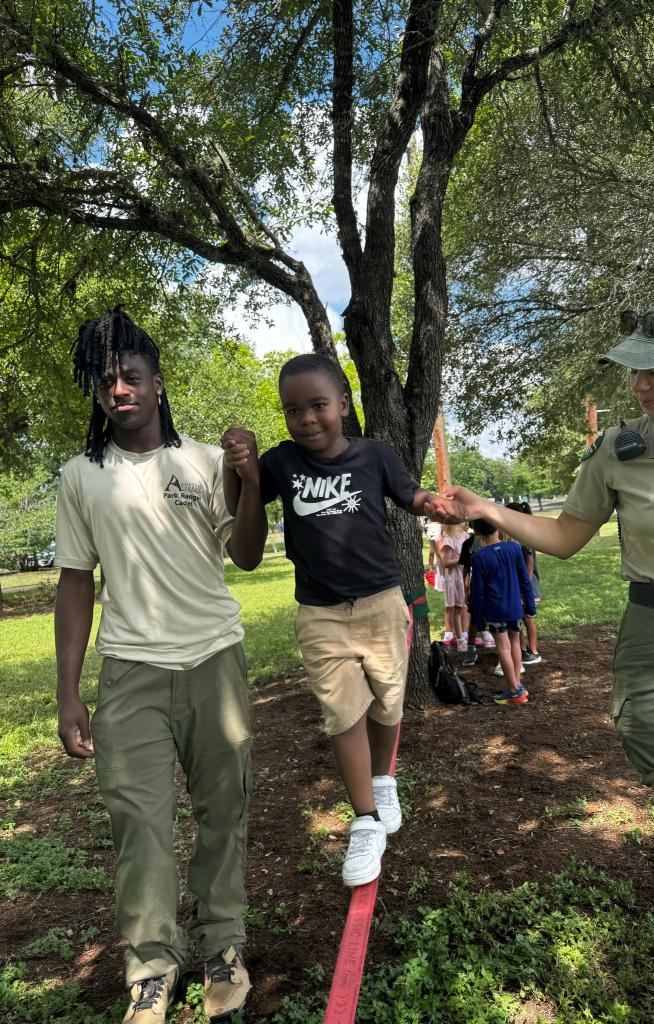 Ranger Cadets helping kid on a slackline.