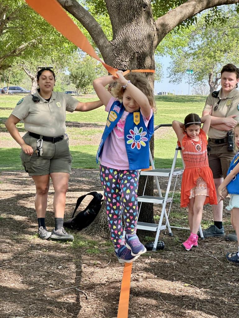 Ranger guiding girls on a slackline.