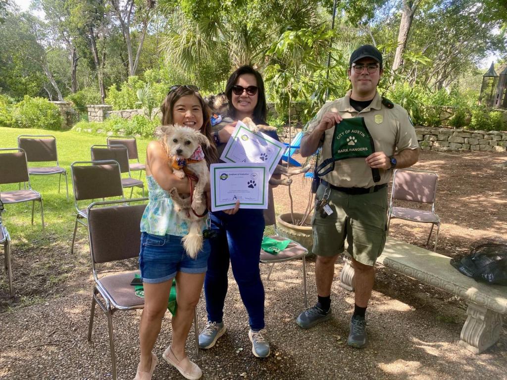 People holding their dog and a certificate next to a Ranger.