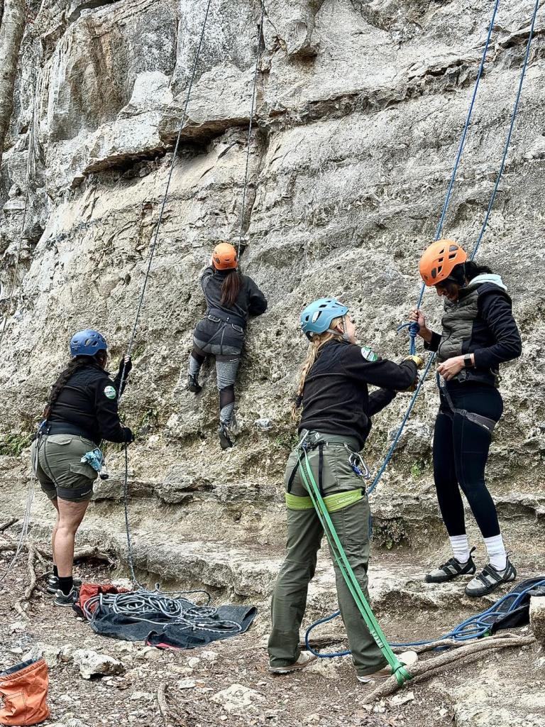 Rangers Belaying and attaching people to ropes near a rock climbing wall.