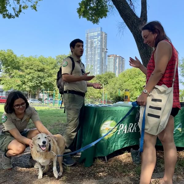 Rangers laughing with people in the park and petting their dog