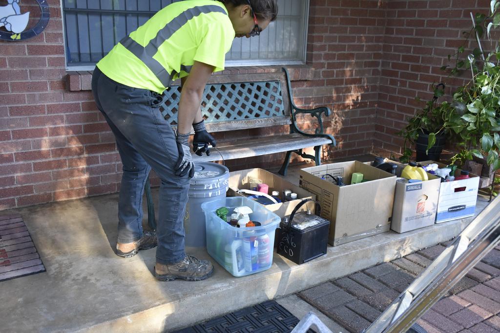 An Austin Resource Recovery worker collects household hazardous waste from the porch of a resident that set up an on-demand collection.