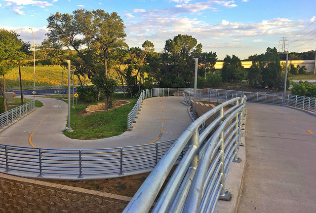 Winding concrete hike and bike trail with railings.