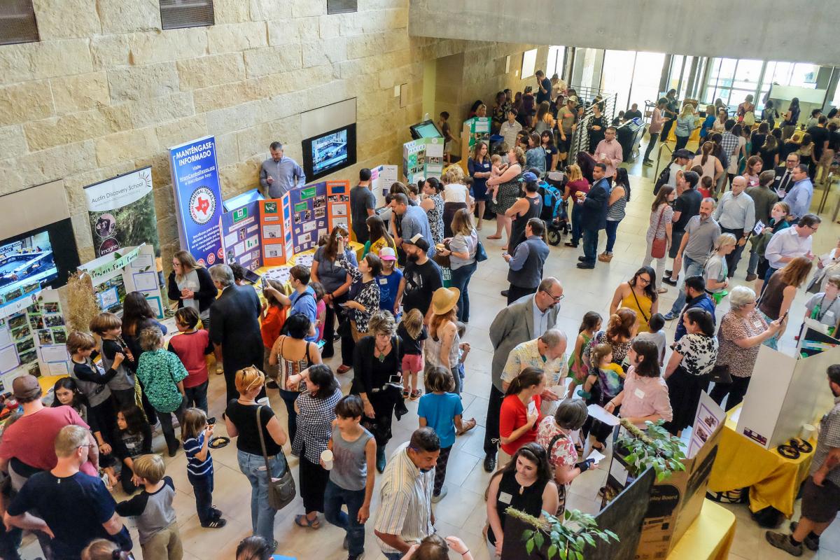 People fill the atrium of Austin City Hall, looking at student project boards