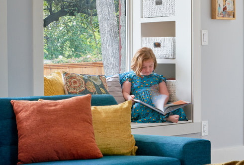 Jerry's granddaughter sitting in a window seat reading a book.