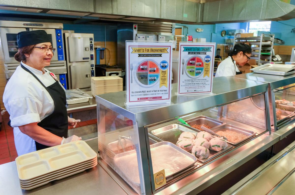 Two people working in a school cafeteria.