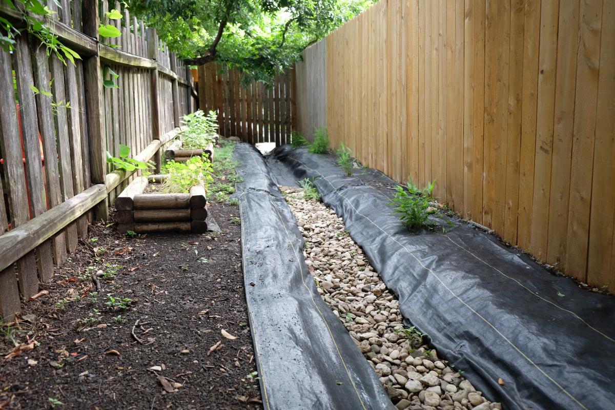 Photo of the lined trench with rocks in it.