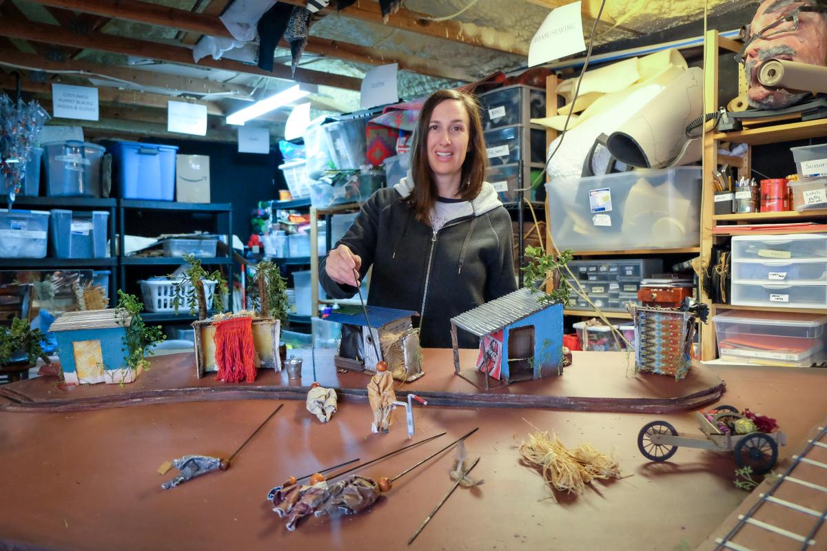 Caroline in her workshop holding a tiny puppet.