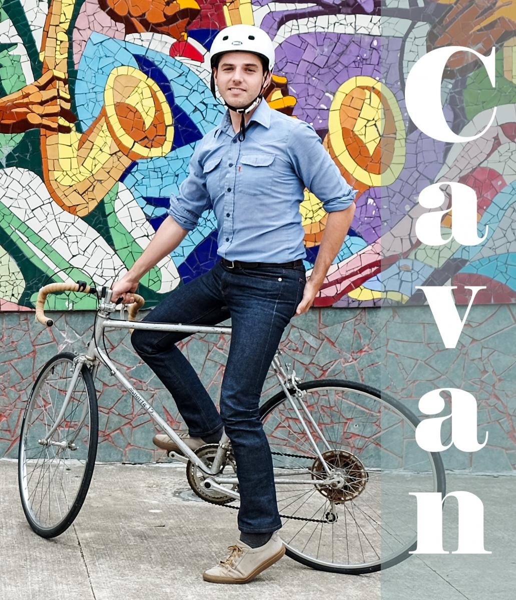 Text: Cavan, pictureof Cavan on a bike with colorful mural in background.