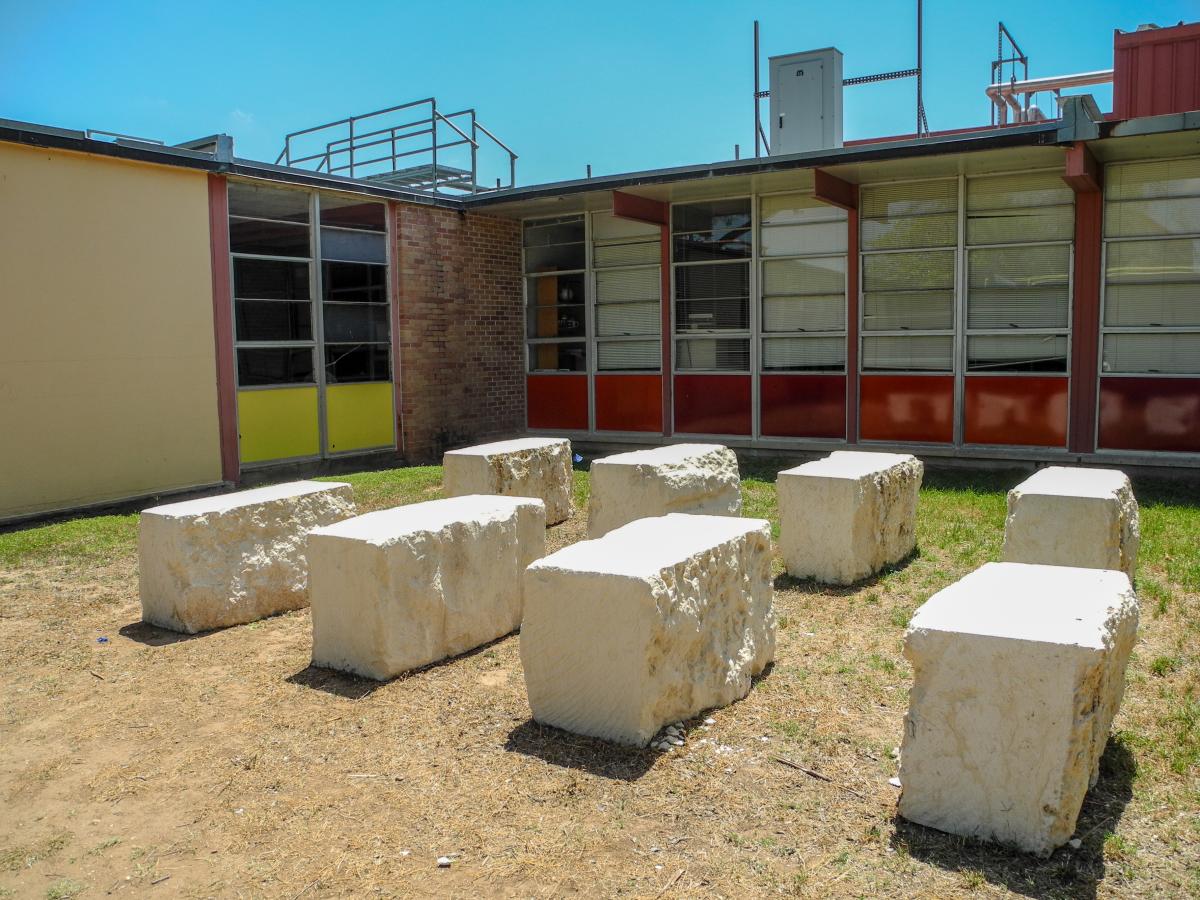 Outdoor classroom made of large stones outside of a school.