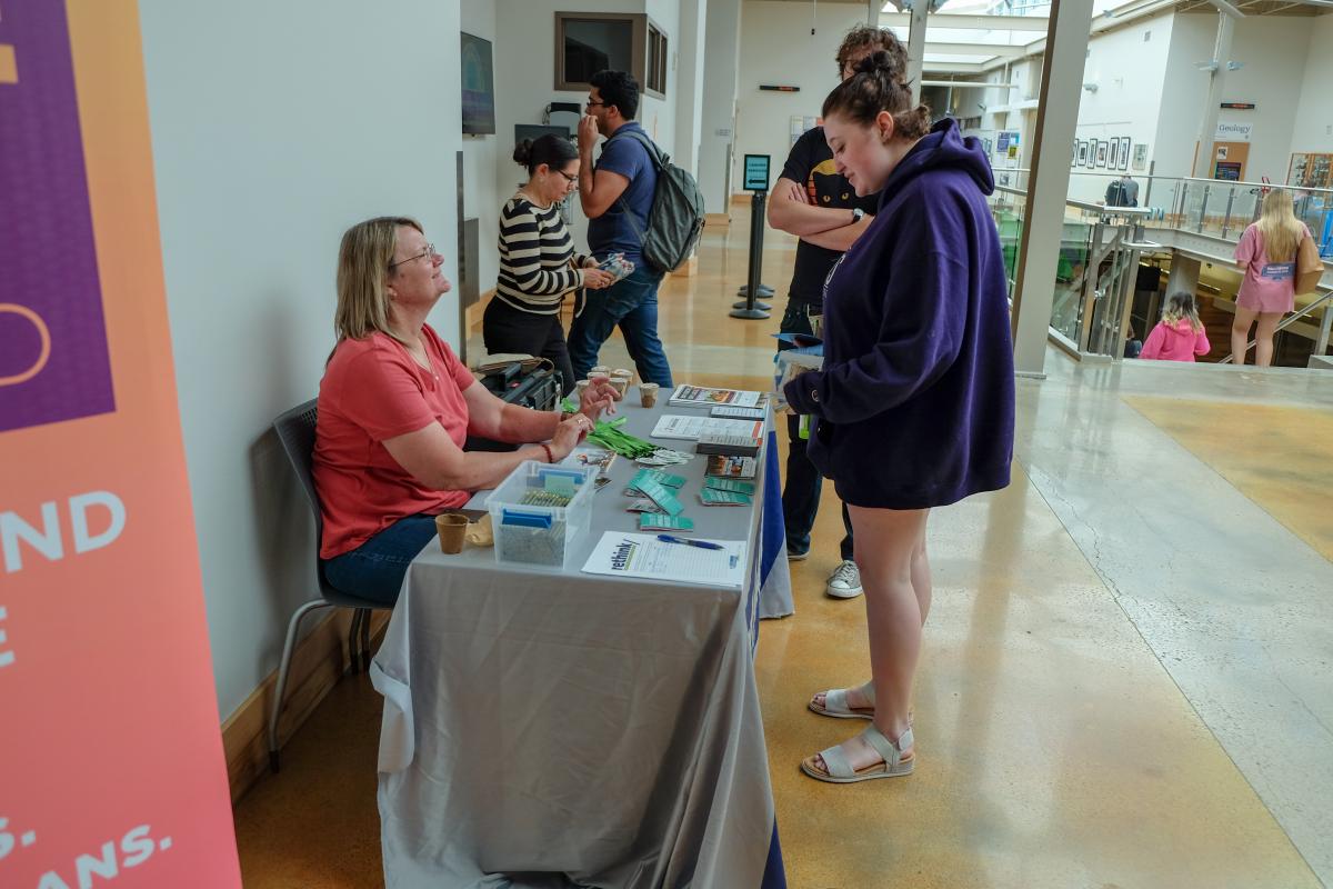 Photo of two people talking to someone who is staffing an outreach table.