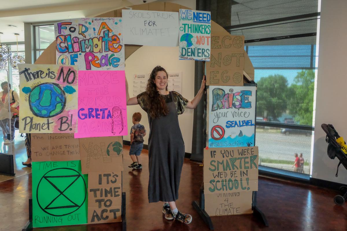 Artist Calder Kamin stands in an archway lined with protest signage.