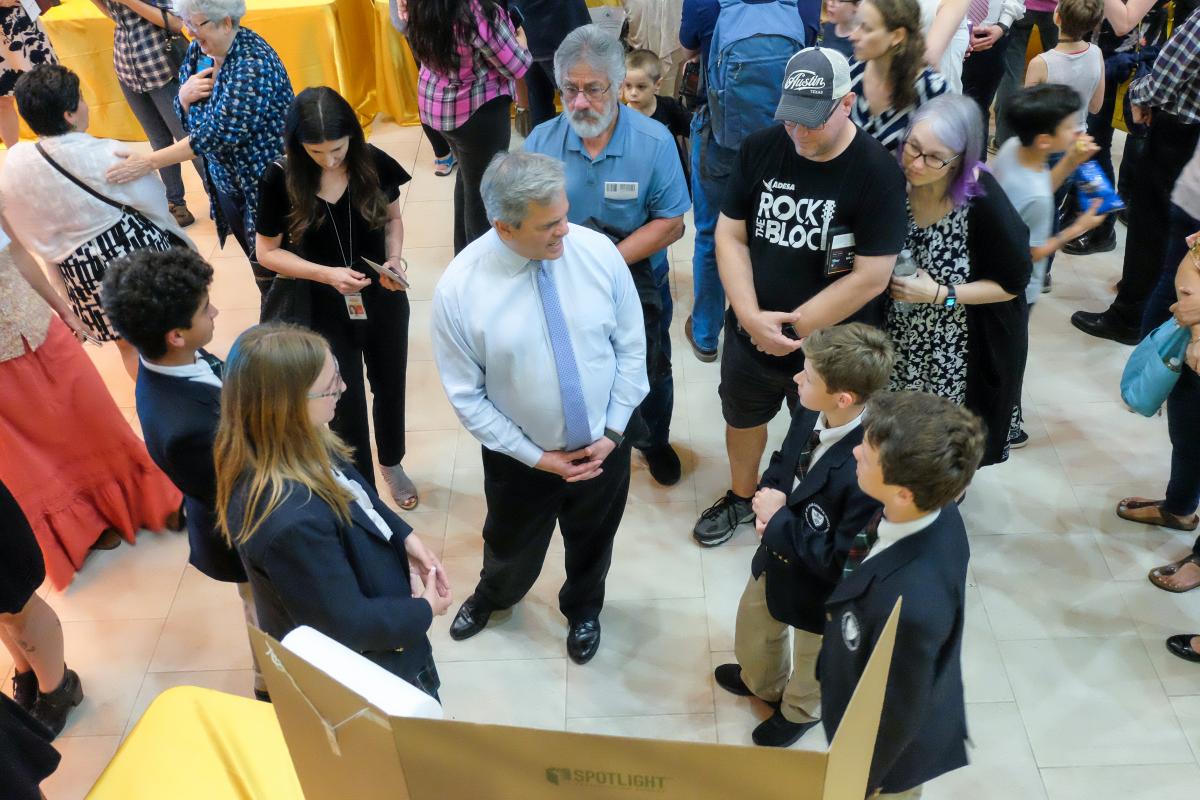 Mayor Steve Adler speaks with students about their sustainability projects. The photo is taken from above.
