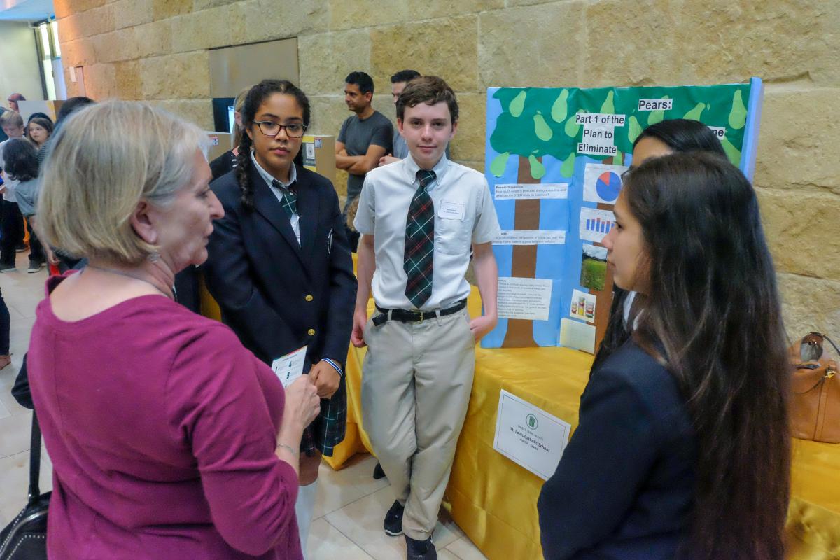 Students speaking to an adult about their sustainable projects.