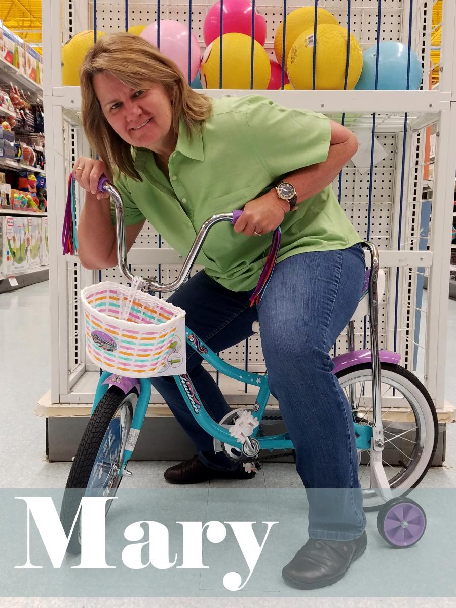 Text: Mary, picture of adult Mary on a child's bike with a basket
