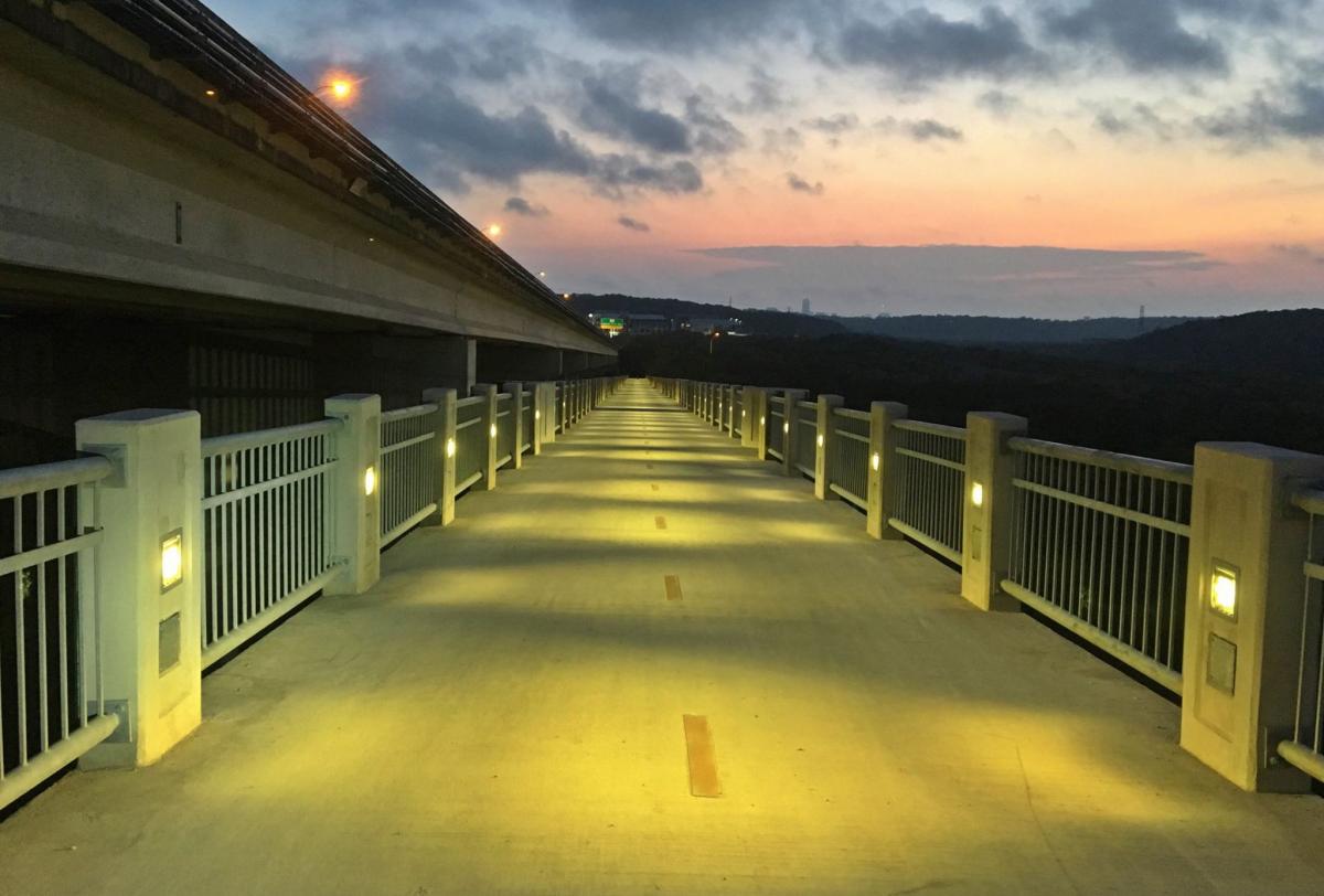 Lit pedestrian bridge at sunrise.