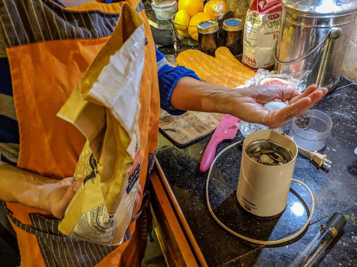 Rosie placing sugar and vanilla pods in spice grinder.