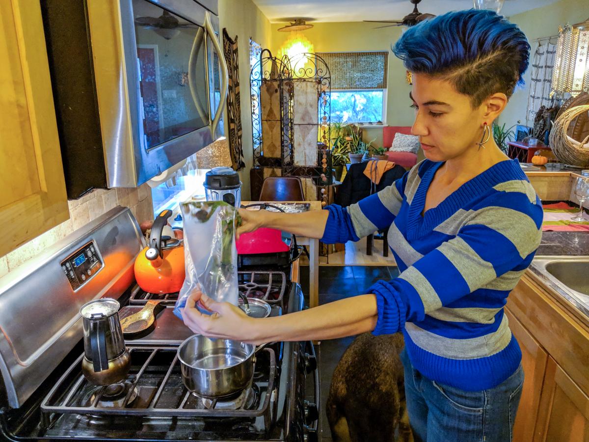 Rosie in her kitchen pouring vegetables out of a ziplock back into a pot.