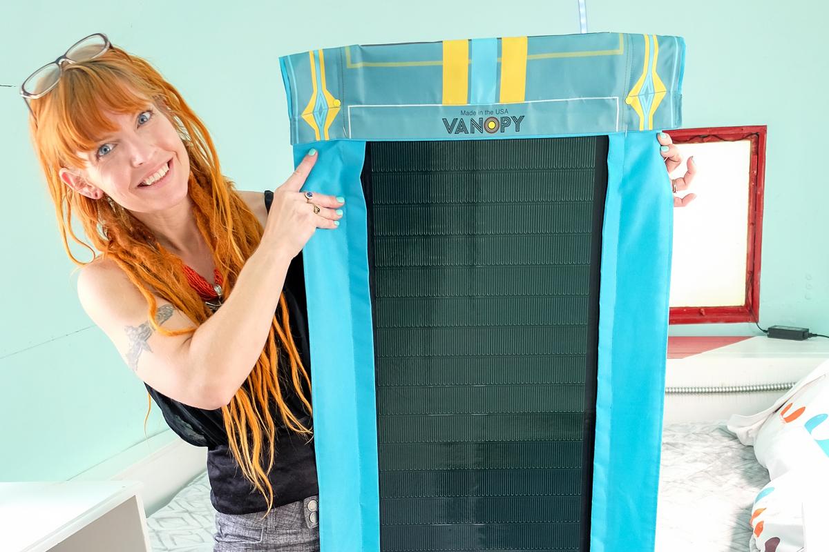 Woman holding a blue cloth rectangular piece with solar panels in the center of it.