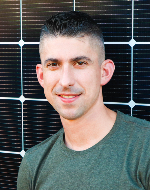 Headshot of Tom Myers with solar panels in the background.