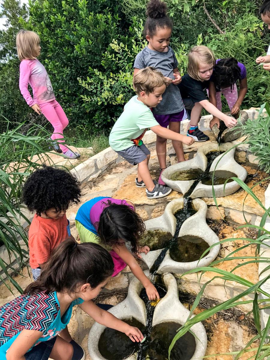 Children enjoying the pond's water fountain