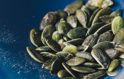 Roasted pumpkin seeds in a blue bowl.